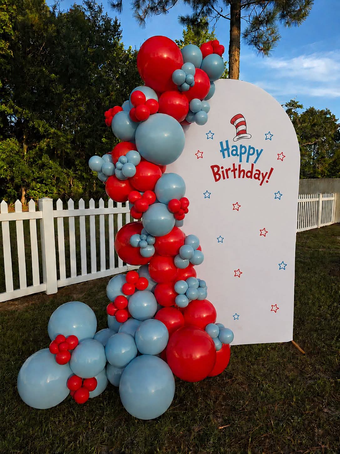 Red and dusty blue garland on a white arched birthday backdrop