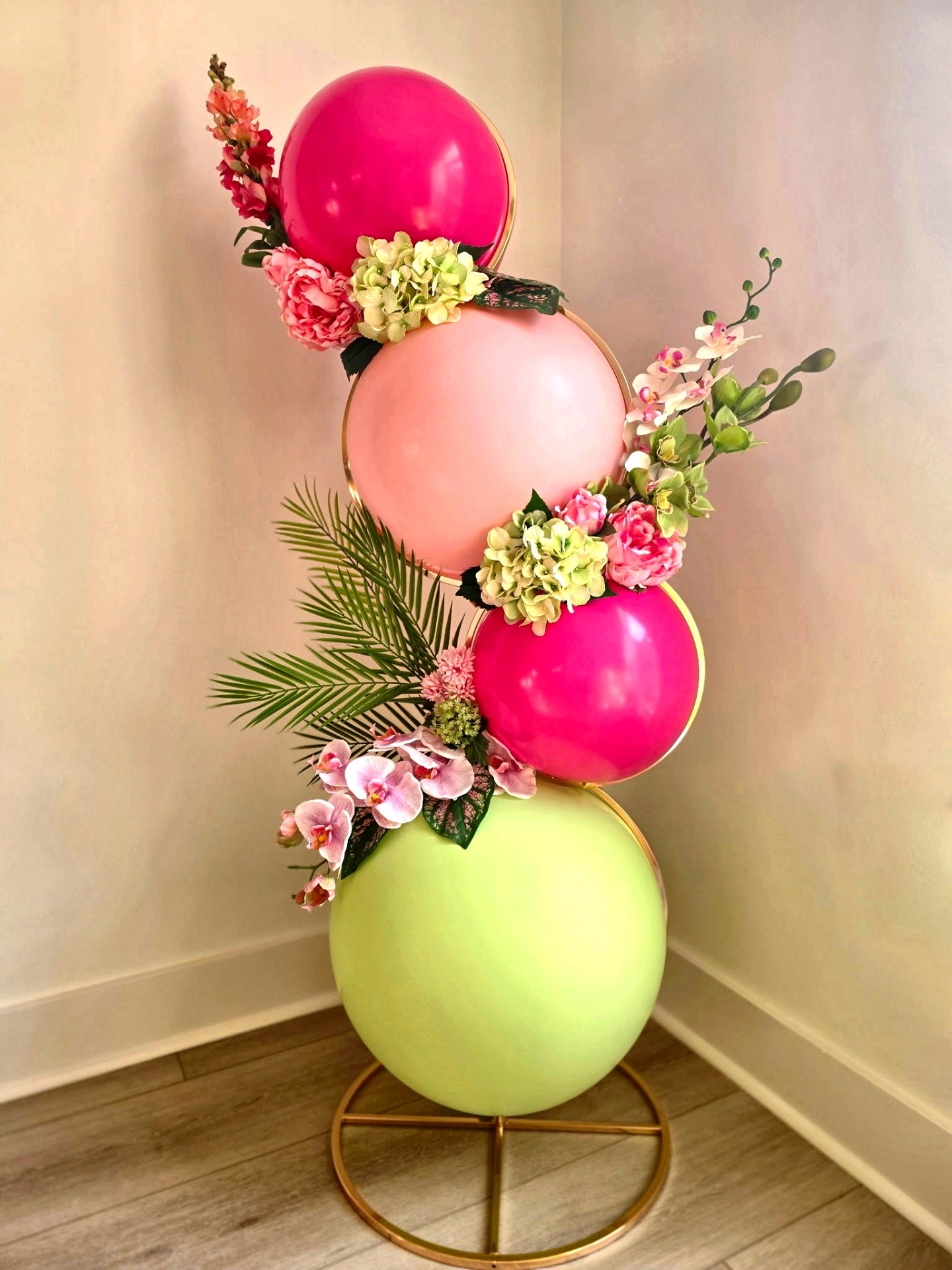 Pink and lime balloons with fresh florals on a gold stand